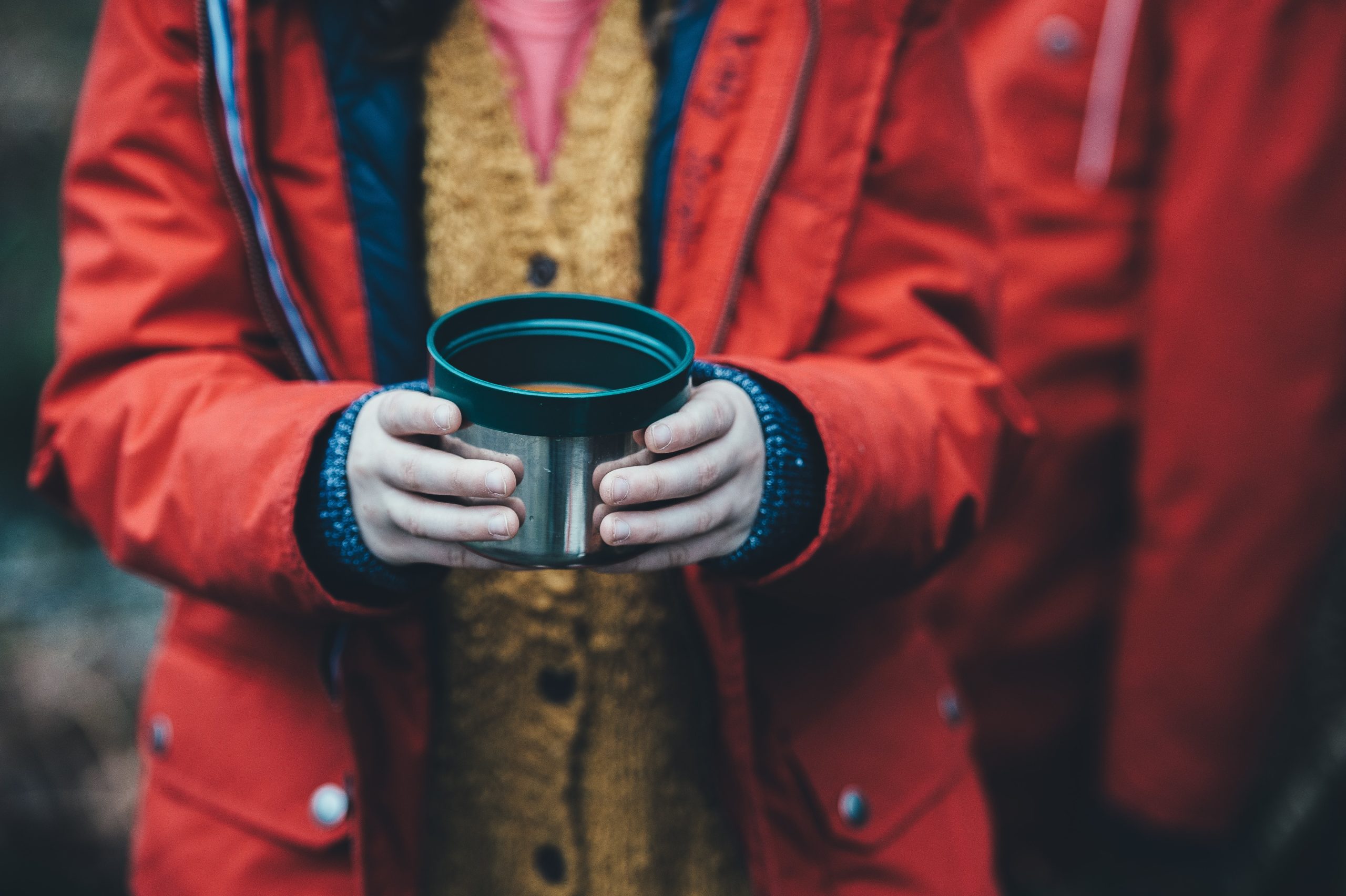 Person holding soup in a thermos lid