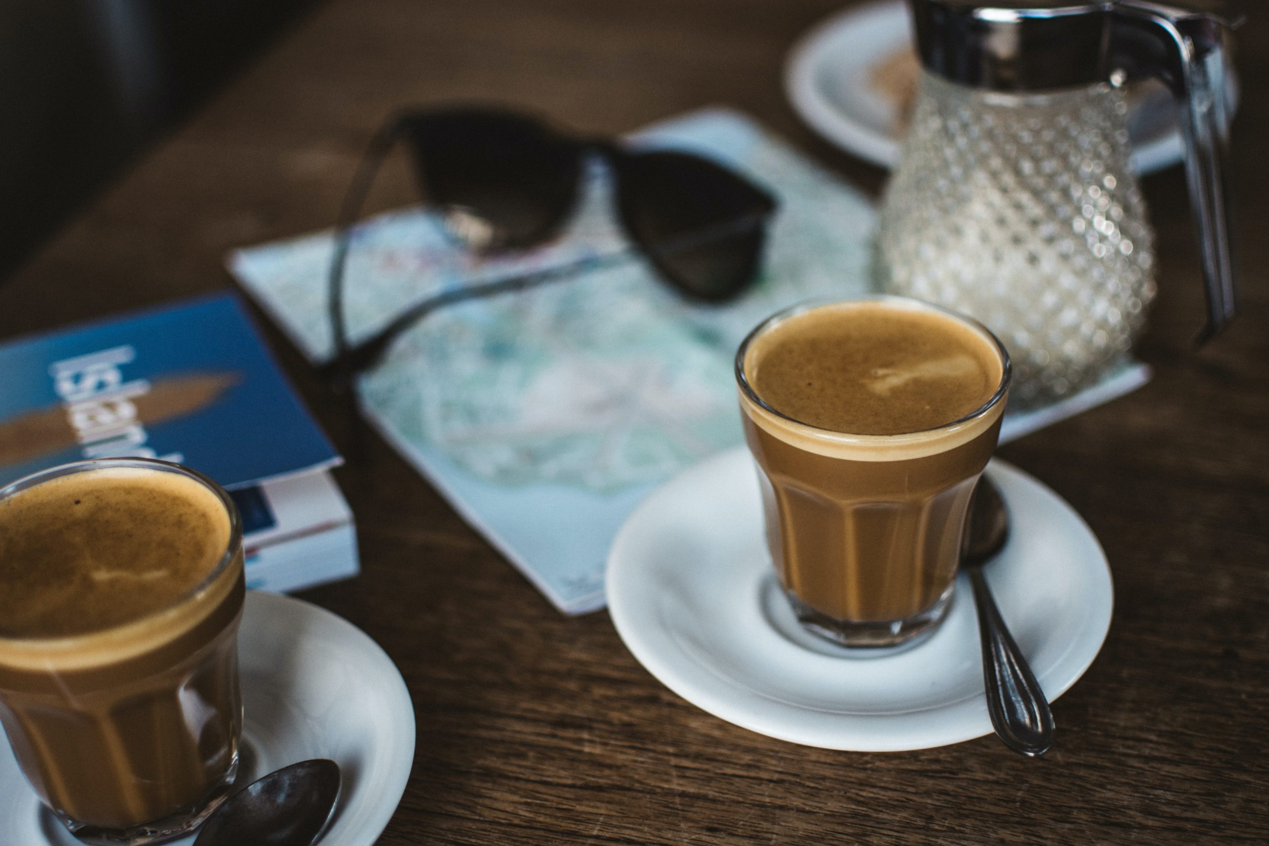 A table with coffee cups and travel books on it